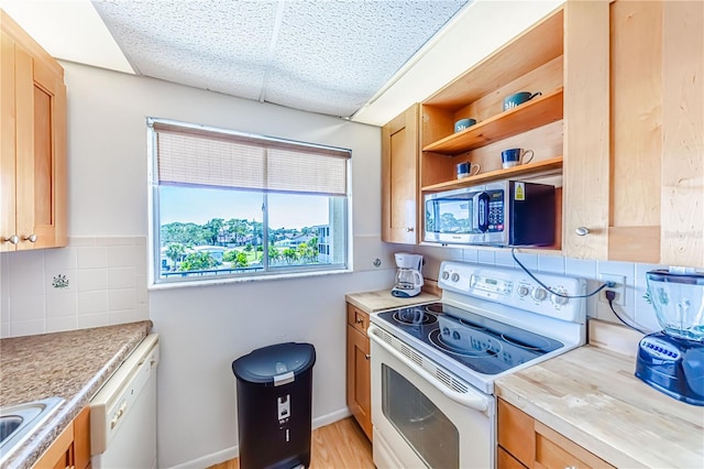 kitchen featuring backsplash, light wood-type flooring, and white appliances