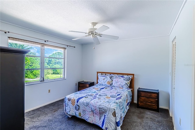 bedroom featuring a textured ceiling, dark carpet, and ceiling fan