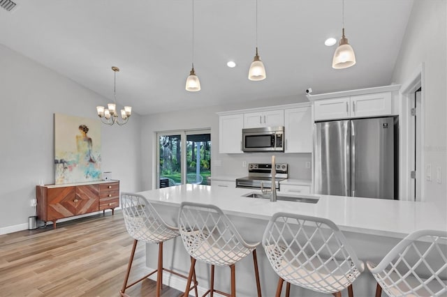 kitchen featuring hanging light fixtures, light hardwood / wood-style flooring, appliances with stainless steel finishes, and white cabinets