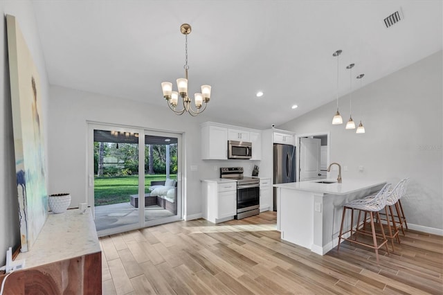 kitchen with light wood-type flooring, white cabinetry, stainless steel appliances, a breakfast bar, and lofted ceiling