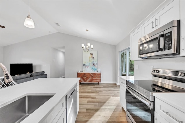 kitchen with light wood-type flooring, pendant lighting, white cabinetry, stainless steel appliances, and lofted ceiling