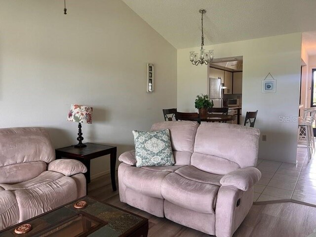 living room featuring lofted ceiling, a chandelier, and wood-type flooring