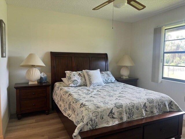 bedroom with multiple windows, ceiling fan, hardwood / wood-style floors, and a textured ceiling