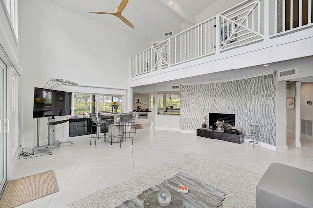 tiled living room with ceiling fan and a high ceiling