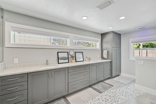 interior space with a wealth of natural light, light stone counters, and sink