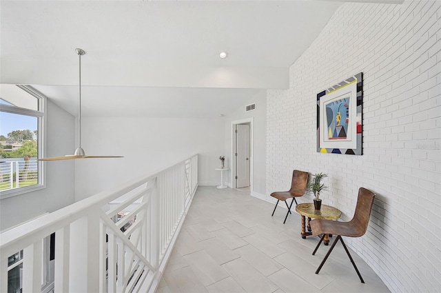 corridor featuring vaulted ceiling, brick wall, and light tile patterned floors