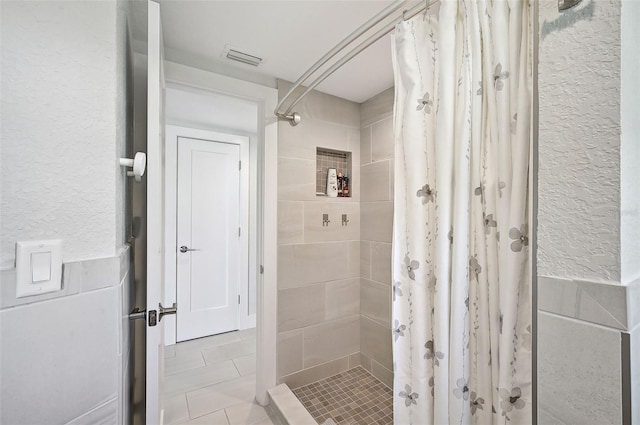 bathroom featuring a shower with shower curtain, tile patterned flooring, and tile walls