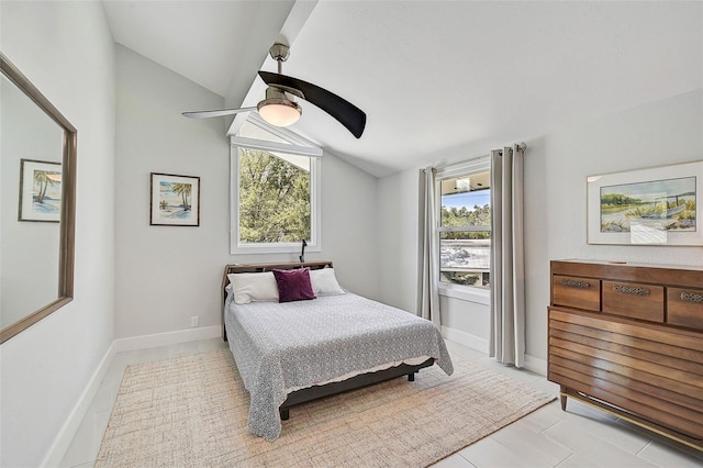 tiled bedroom featuring multiple windows, ceiling fan, and vaulted ceiling