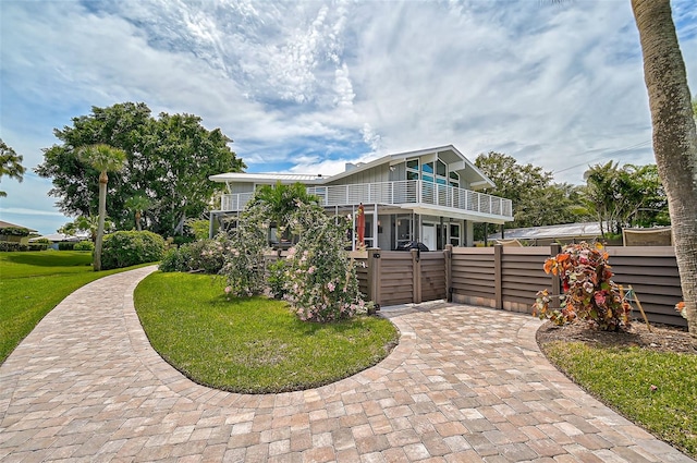 view of front of property featuring a balcony and a front lawn