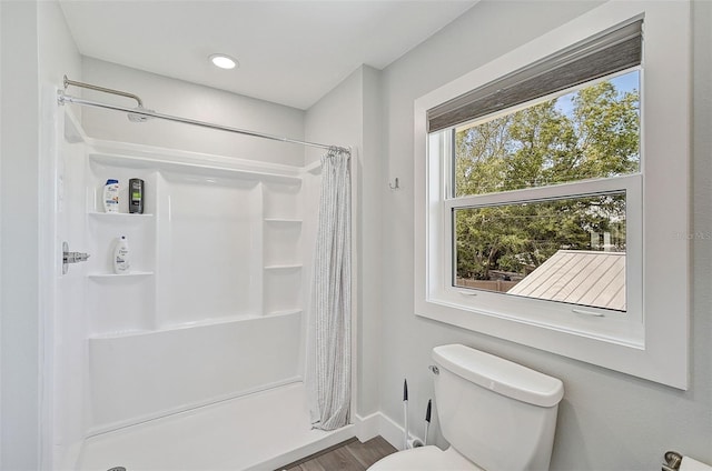 bathroom with hardwood / wood-style flooring, toilet, and a shower with shower curtain