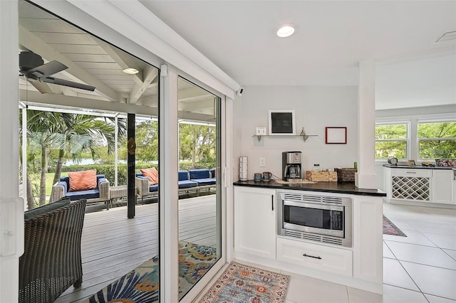 kitchen featuring stainless steel microwave, white cabinetry, plenty of natural light, and ceiling fan