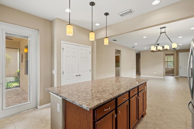 kitchen with decorative light fixtures, a center island, light stone countertops, and an inviting chandelier