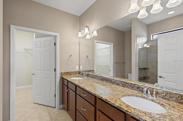 bathroom with a tile shower, tile patterned flooring, and vanity