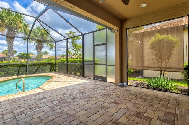 view of swimming pool with glass enclosure, ceiling fan, and a patio area