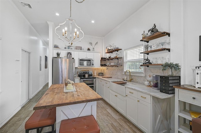 kitchen featuring light wood-type flooring, white cabinetry, butcher block countertops, stainless steel appliances, and a center island