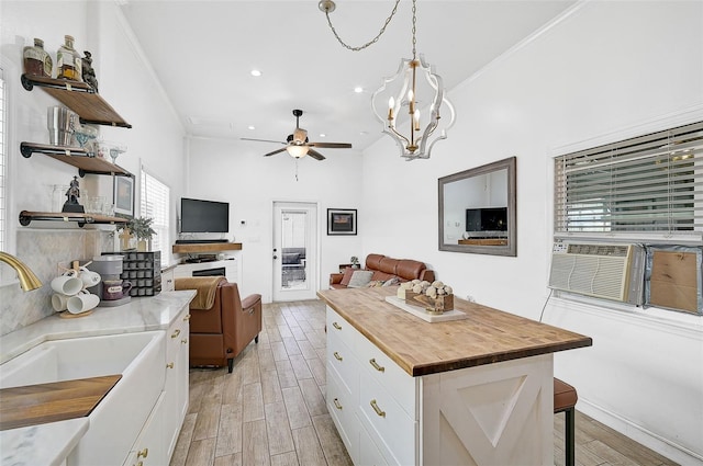 kitchen featuring a wealth of natural light, a kitchen island, butcher block countertops, and white cabinetry