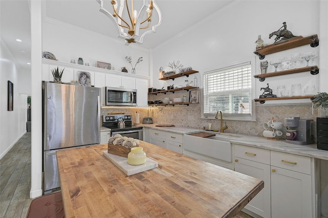 kitchen with appliances with stainless steel finishes, white cabinetry, and butcher block counters