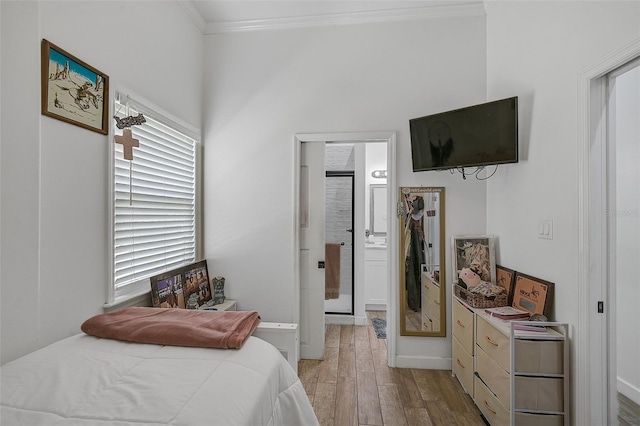 bedroom featuring crown molding, light hardwood / wood-style flooring, and connected bathroom