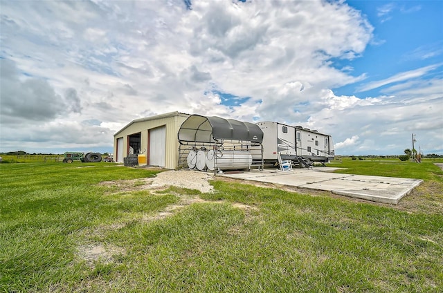 back of house featuring a yard, an outbuilding, a rural view, and a carport