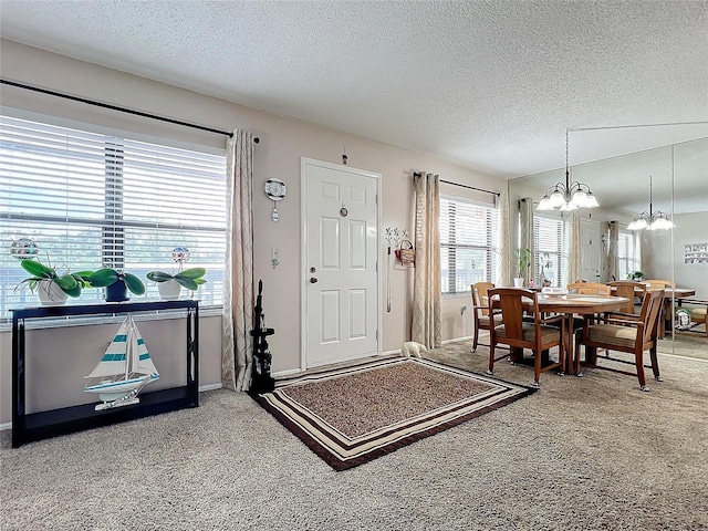 carpeted foyer entrance with a chandelier and a textured ceiling