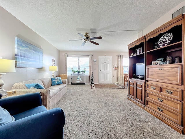 carpeted living room featuring ceiling fan and a textured ceiling