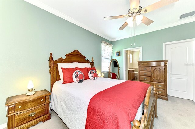 bedroom with ceiling fan, light colored carpet, ornamental molding, and ensuite bath