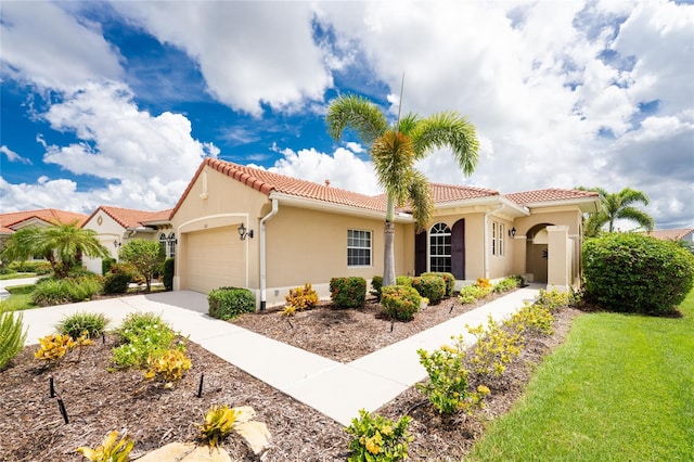 mediterranean / spanish-style house featuring a garage and a front lawn