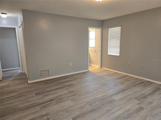 unfurnished room featuring wood finished floors, visible vents, and baseboards