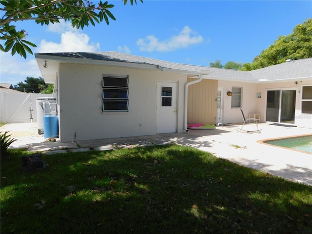 rear view of house featuring fence, stucco siding, a yard, a patio area, and a gate