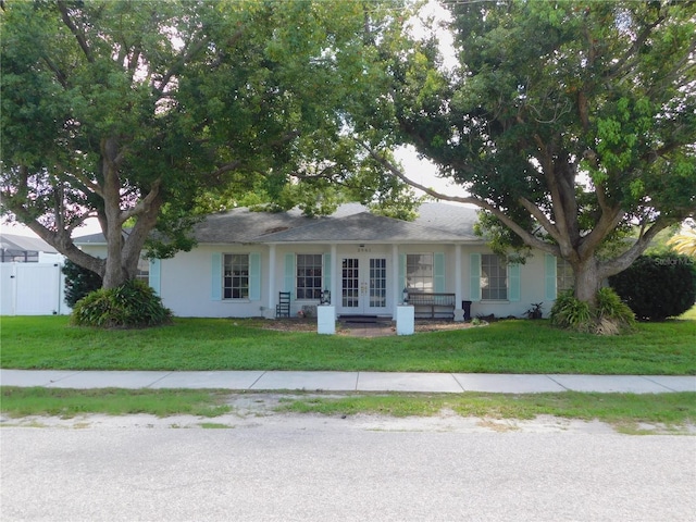 ranch-style house with french doors, a front yard, stucco siding, and fence