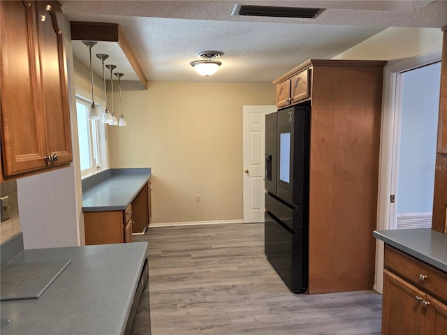 kitchen featuring a textured ceiling, light wood-type flooring, visible vents, and black fridge