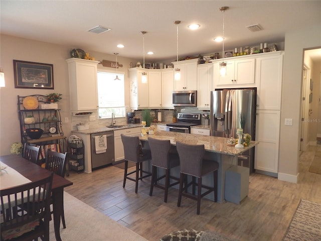 kitchen featuring appliances with stainless steel finishes, hardwood / wood-style flooring, a center island, and white cabinets