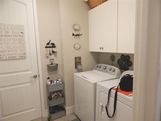 washroom with hardwood / wood-style flooring, cabinets, and washing machine and dryer