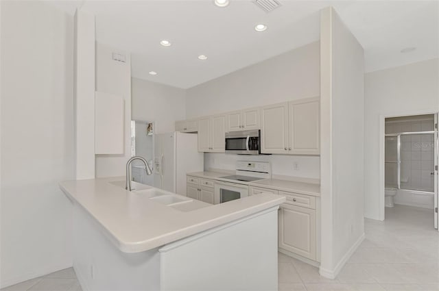 kitchen with kitchen peninsula, sink, white appliances, and light tile patterned flooring