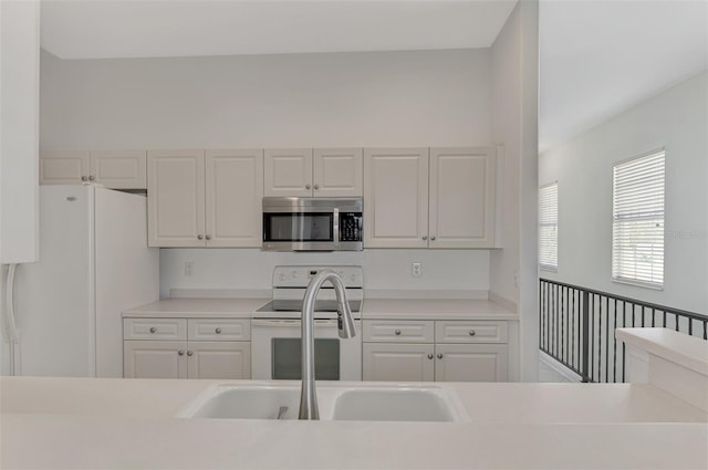 kitchen with sink, white appliances, and white cabinetry