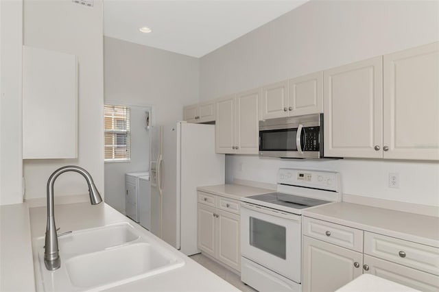 kitchen with white cabinets, white appliances, sink, and washer and dryer