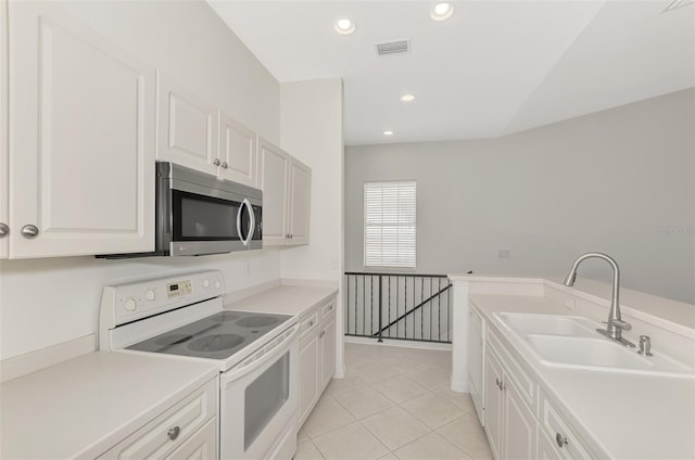 kitchen with sink, light tile patterned floors, white electric range oven, and white cabinets