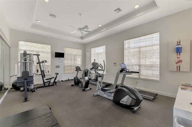 gym with ceiling fan, ornamental molding, and a tray ceiling