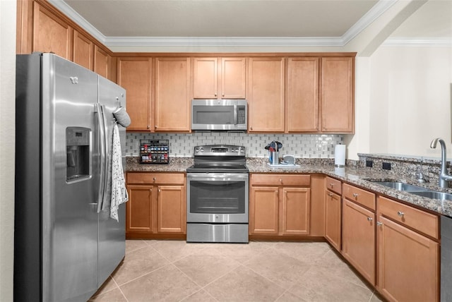 kitchen with dark stone counters, crown molding, light tile patterned floors, sink, and appliances with stainless steel finishes