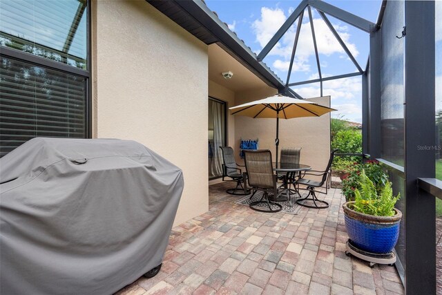 view of patio / terrace featuring glass enclosure and a grill