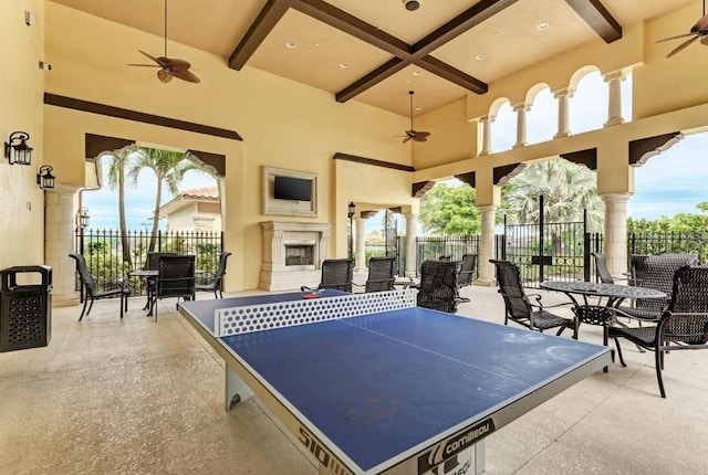 recreation room with ceiling fan, exterior fireplace, beamed ceiling, and coffered ceiling