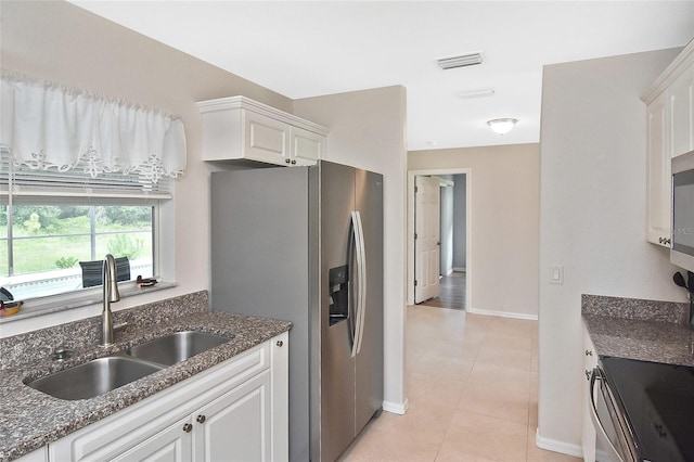 kitchen with white cabinets, sink, stainless steel fridge, light tile patterned floors, and range