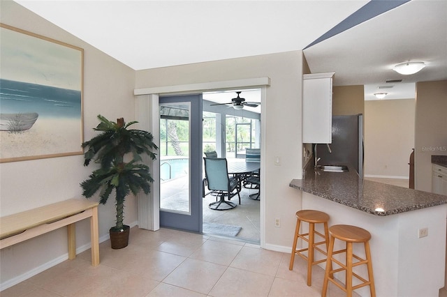 kitchen featuring a breakfast bar, white cabinetry, kitchen peninsula, and stainless steel refrigerator