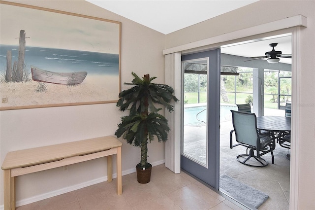 doorway featuring light tile patterned floors, vaulted ceiling, and ceiling fan