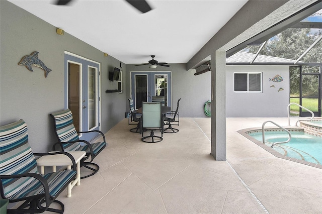 exterior space featuring glass enclosure, french doors, ceiling fan, a patio, and a hot tub