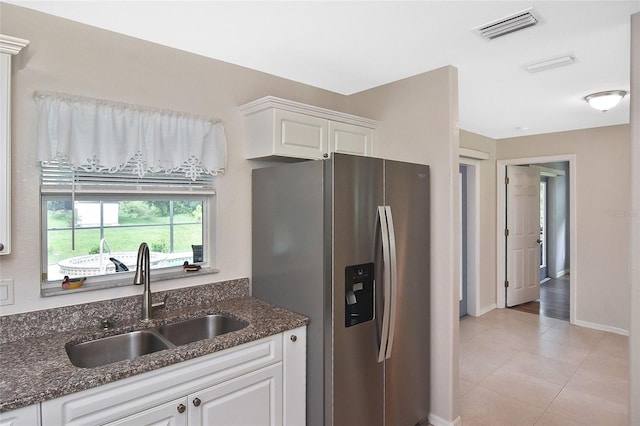 kitchen featuring white cabinets, sink, stainless steel fridge, dark stone countertops, and light tile patterned floors