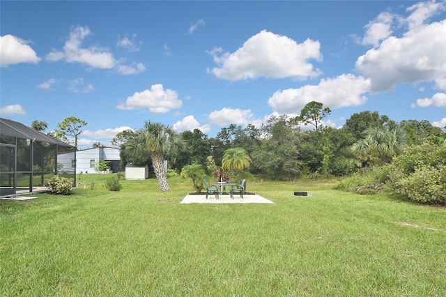 view of yard featuring glass enclosure and a patio