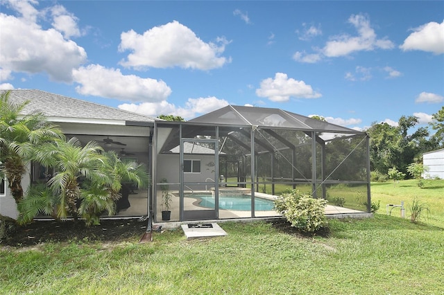 view of swimming pool with a yard, ceiling fan, and a lanai