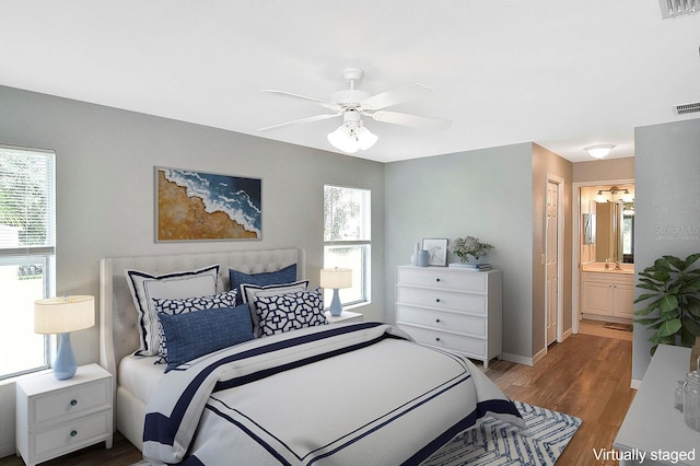 bedroom featuring ceiling fan, sink, light hardwood / wood-style flooring, and ensuite bath