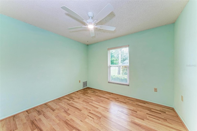 unfurnished room with a textured ceiling, light wood-type flooring, and ceiling fan